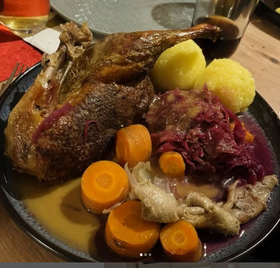 Ein Teller mit Braten, Kartoffeln, Rotkohl und Karotten.