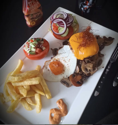 Ein Teller mit Burger, Spiegelei, Pommes, Salat und Salsa.