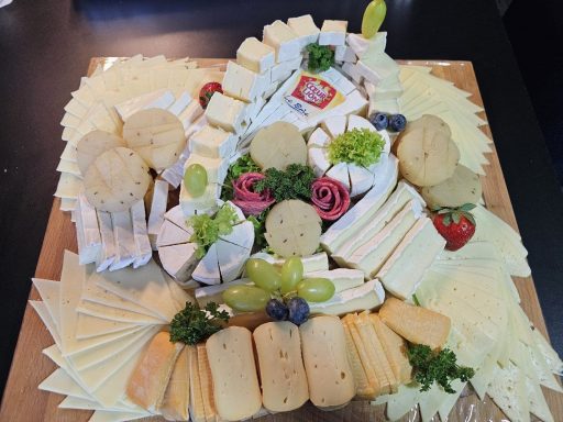 Käseplatte mit verschiedenen Käsesorten, Trauben, Kräutern und knusprigem Brot.