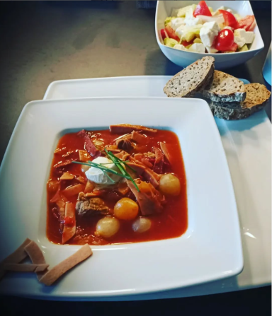 Herzhafter Eintopf mit Fleisch, Gemüse und Sahne, begleitet von Brot und einem Salat.