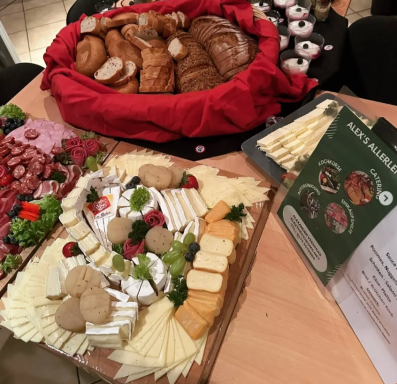 Ein gedeckter Tisch mit verschiedenen Brotsorten, Käseplatten und Aufschnitt.
